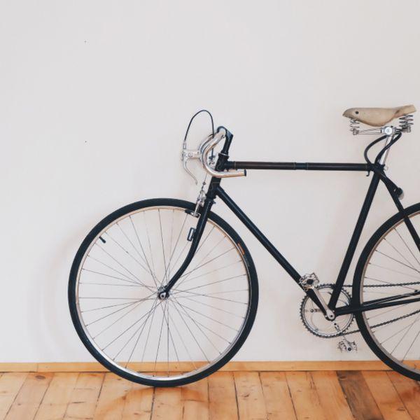 Schwarzes Vintage-Rennrad, das an einer weißen Wand lehnt